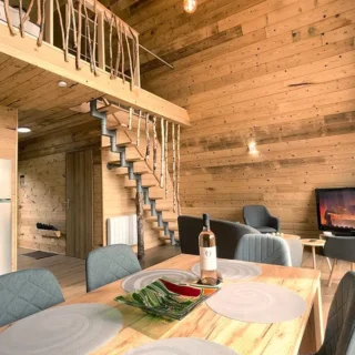 Salle à manger ouverte et salon cosy au Chalet Charkhan - Gérardmer Table à manger conviviale avec vue sur le salon et la mezzanine boisée du Chalet Charkhan, Atypiques Chalets Gérardmer.