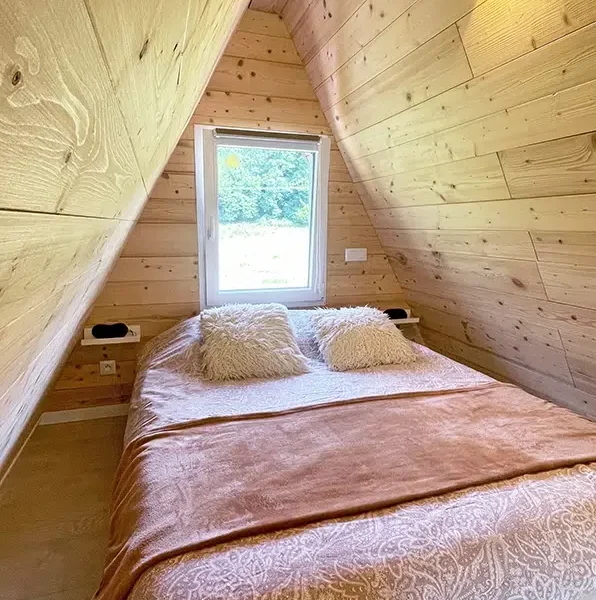 Chambre en mezzanine du chalet A-Frame Iorik – Gérardmer Chambre en mezzanine du chalet A-Frame Iorik, lit double sous la charpente en bois, à 10 min de Gérardmer