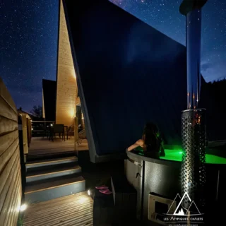 bain-nordiques-alsan Bain nordique illuminé de nuit sous un ciel étoilé dans les Vosges aux Atypiques Chalets